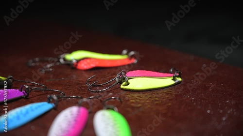 Spinners of different colors and shapes for fishing on a brown table. Background in blur.