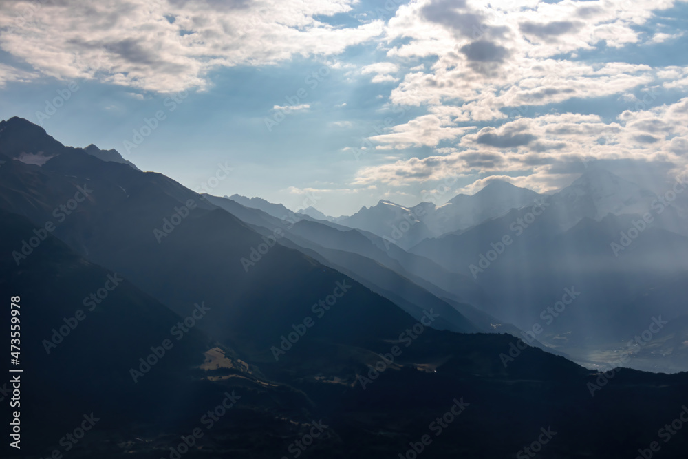 Amazing view on the village of Mestia in the Greater Caucasus Mountain Range, Country of Georgia. The morning fog covers the valley, while the first sun rays appear on the snowy mountain peaks.Sunrise