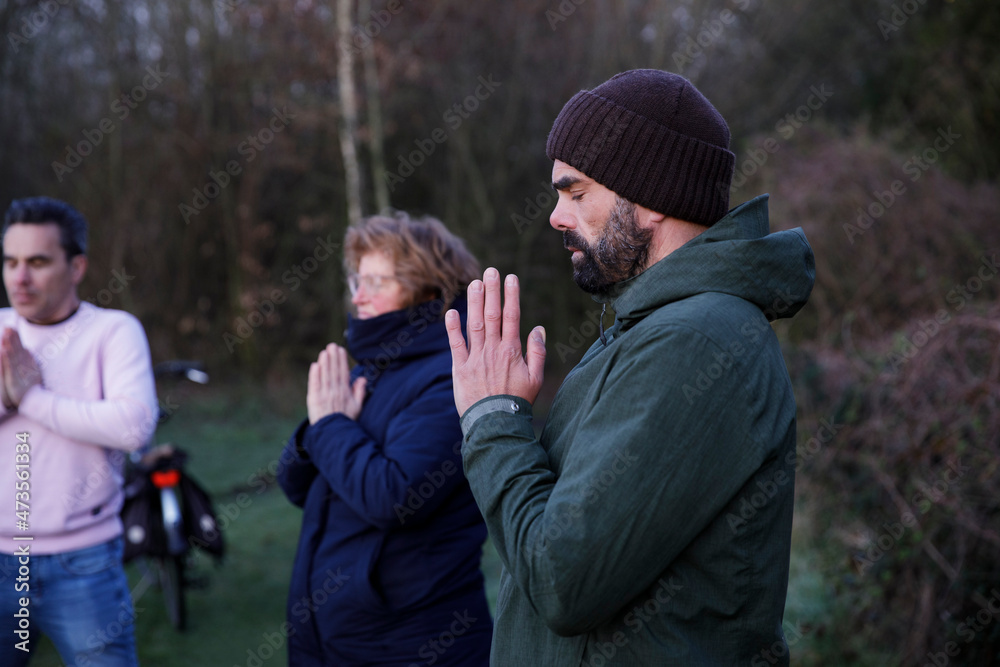 Mature woman and men with eyes closed meditating in nature Mature woman and men with eyes closed meditating in nature