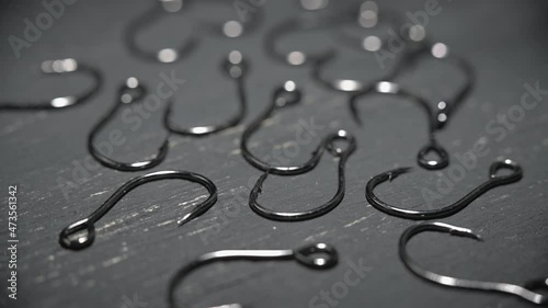 Fishinghooks in close-up are scattered on a dark gray table. photo