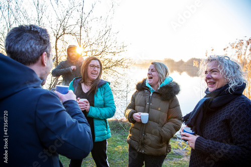 Happy male and female friends talking while having coffee at waterfront