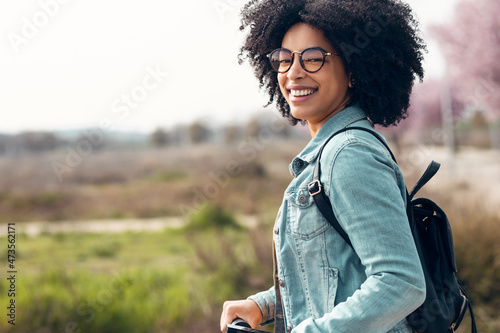 Cheerful woman with eyeglasses smiling while traveling with electric push scooter photo