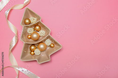 Pink background with gold balls, porcelain dish and packing tape. New Year's decoration. Background. Christmas. Spruce.