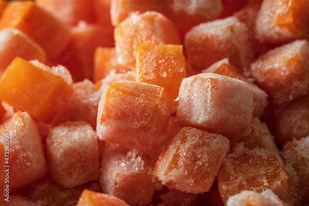 Frozen fresh carrot cube pieces closeup background