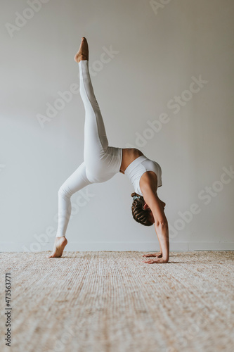 Flexible yogi practicing Eka Pada Urdhva Dhanurasana on carpet at health club