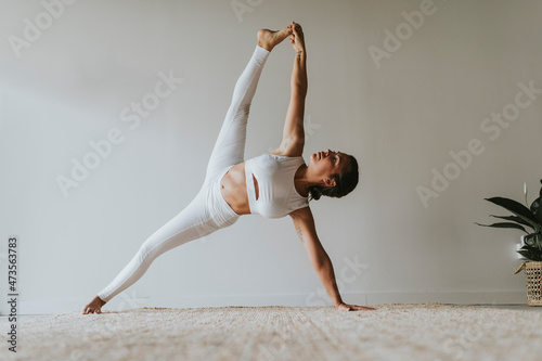 Flexible female yoga instructor with legs apart practicing at health club photo