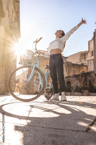 Happy smiling woman rides a bicycle on the city road in baroque square in italy