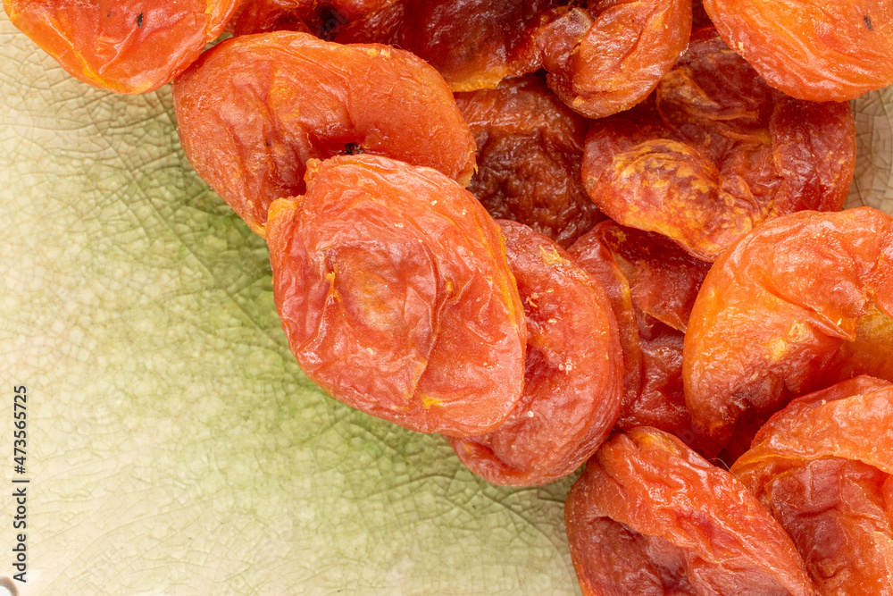 Several sweet dry apricots, close-up on a ceramic dish, top view. Several sweet dry apricots, close-up on a ceramic dish, top view.