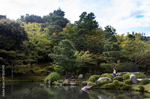 Japan, Kyoto Prefecture, Kyoto, Young woman meditating in front ofSogenPond photo