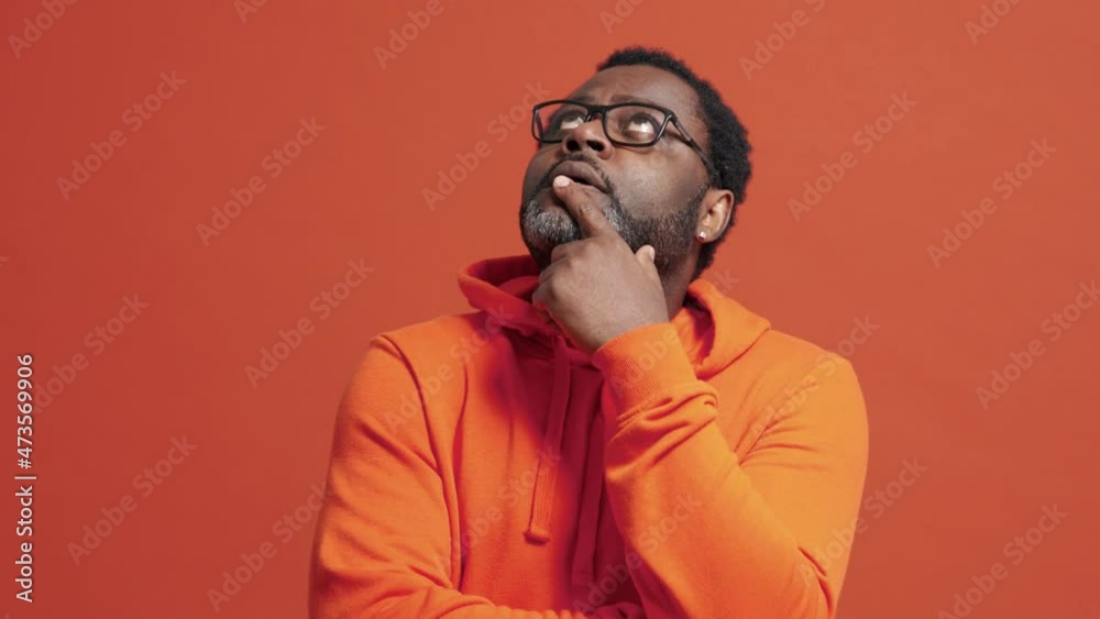 Serious mature African man thinking about something in the orange studio Serious mature African man thinking about something in the orange studio