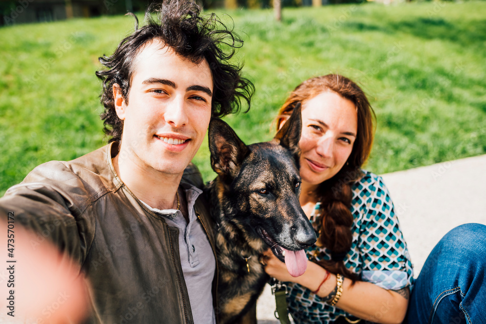 Man smiling while taking selfie with woman and pet Man smiling while taking selfie with woman and pet