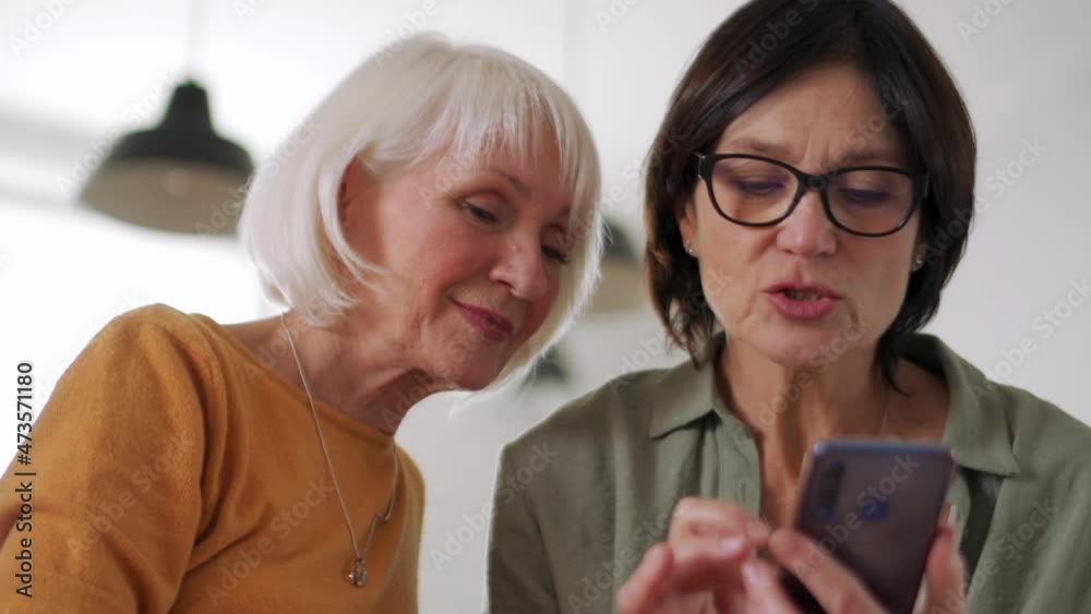 Concentrated middle aged women talking and looking at phone on the sofa at home Concentrated middle aged women talking and looking at phone on the sofa at home