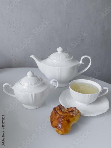 Cup for tea, teapot, sugar bowl, delicious buns on the table for morning tea