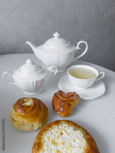 Cup for tea, teapot, sugar bowl, delicious buns on the table for morning tea