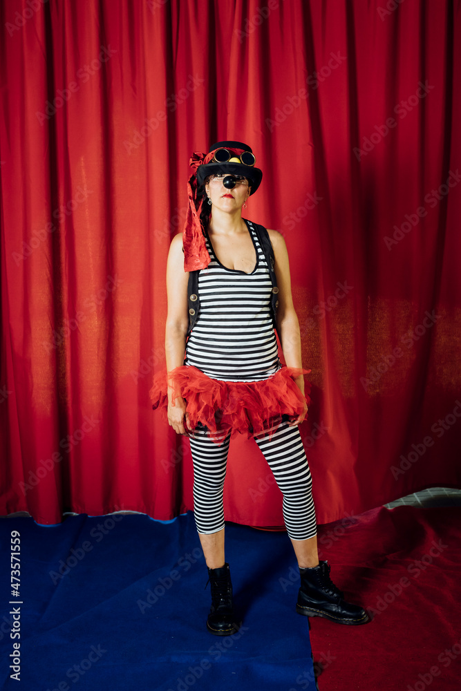 Female clown wearing hat and costume standing on stage