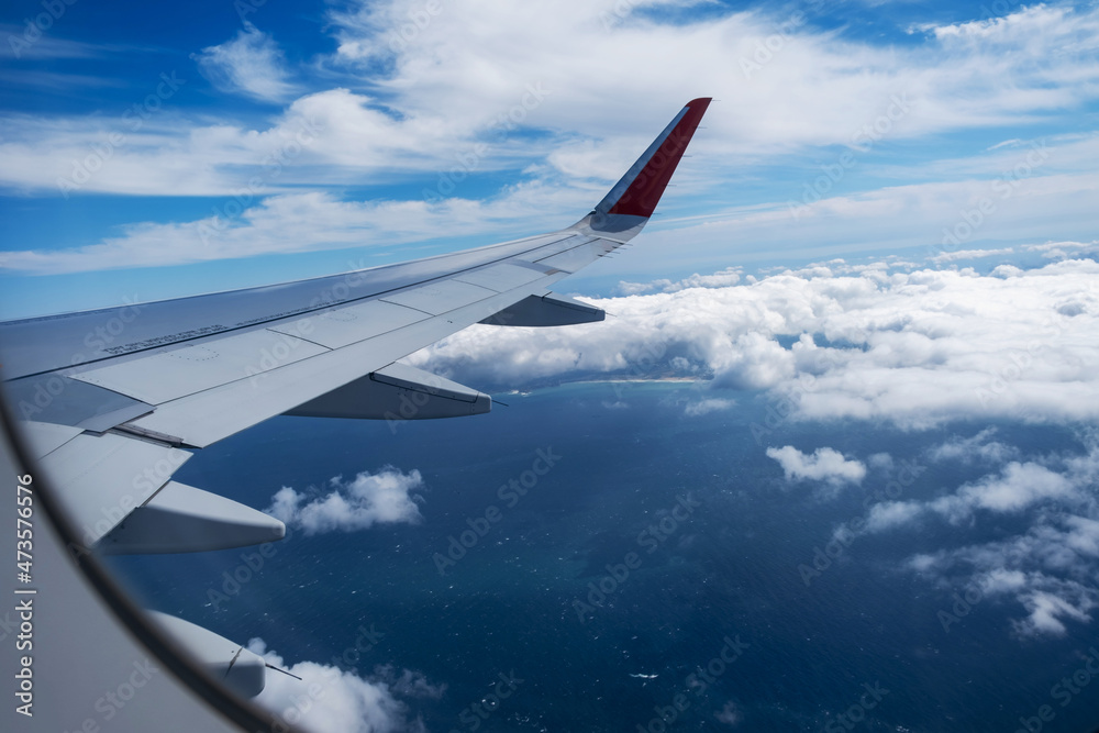 Obraz premium Classic image through aircraft window onto wing. Flight view over sea in cloudy weather