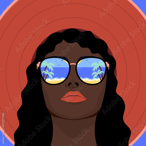Woman in sunglasses and hat with reflection of beach