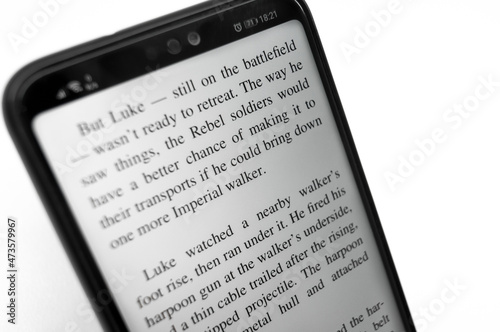 E-book on the screen of a smartphone. Reading electronic books on your mobile phone. The text on the screen. Selective focus, copy space.