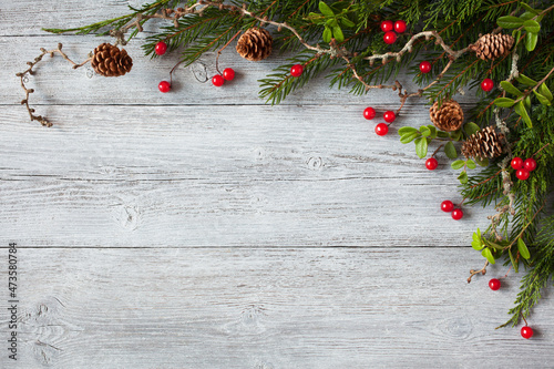 Foto Christmas wooden background with spruce branches, larch, thuja, cones, lingonberry leaves and red berries