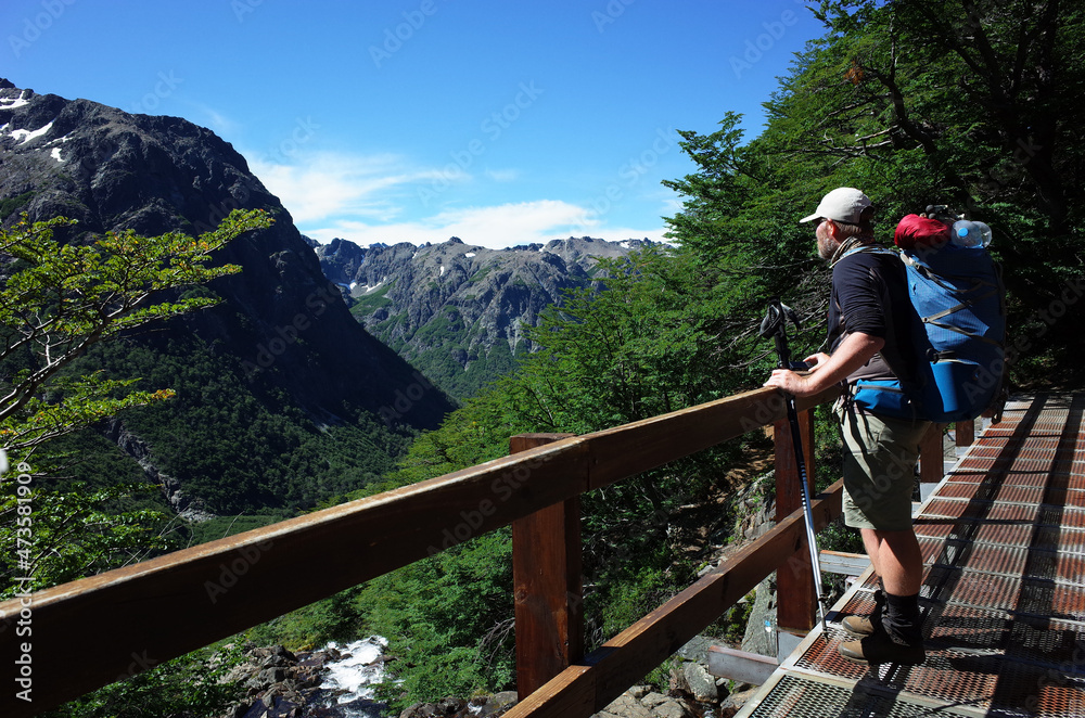 Man with big backpack standing on bridge with green mountain view in Nahuel Huapi national park, Hiking in Patagonia, Argentina Man with big backpack standing on bridge with green mountain view in Nahuel Huapi national park, Hiking in Patagonia, Argentina