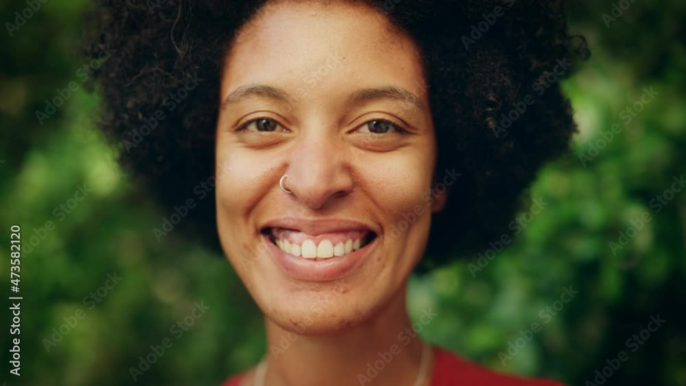 Close Up Portrait of a Happy Young Latina with Brown Eyes, Afro Hair and Nose Piercing Posing for Camera. Beautiful Diverse Multiethnic Black Hispanic Female Smiling on Green Nature Background. Close Up Portrait of a Happy Young Latina with Brown Eyes, Afro Hair and Nose Piercing Posing for Camera. Beautiful Diverse Multiethnic Black Hispanic Female Smiling on Green Nature Background.