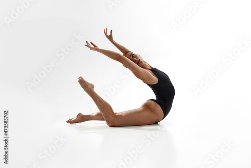 Young woman dancing ballet on white background