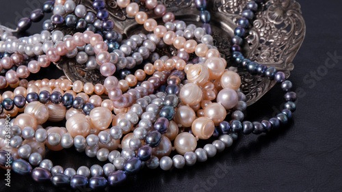 Sparkling iridescent multi colored pearl necklaces on a black background. Retro composition