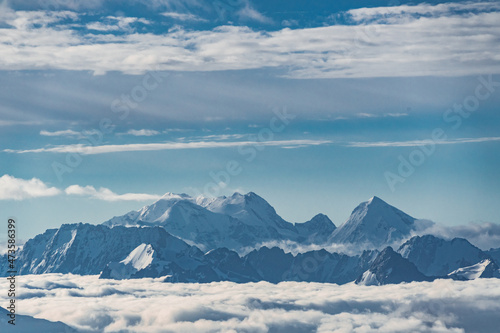 Beautiful panorama of high rocky mountains with mighty glaciers and snowy peaks against the blue sky and clouds