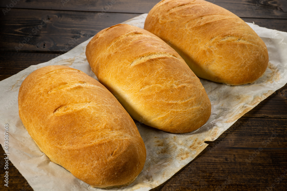 fresh baked loaves of bread on lie on a dark wooden table