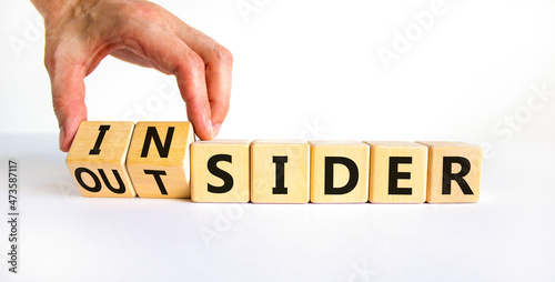Insider or outsider symbol. Businessman turns a cube, changes the word insider to outsider. Beautiful white table, white background. Business, insider or outsider concept. Copy space. photo