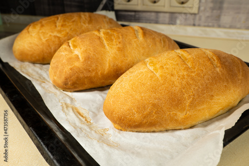 freshly baked loaves bread on a black baking sheet