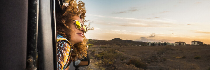 Happy woman traveling on car outside the windows enjoying wind and freedom admire the sunset. Banner header for travel lifestyle concept