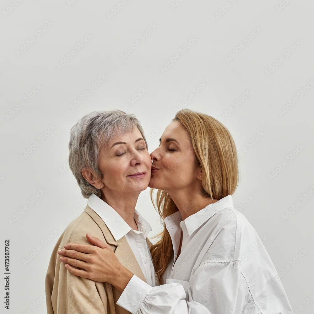 Loving grownup daughter kiss mature mom in cheek - obrazy, fototapety, plakaty 