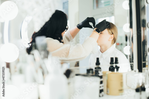Obraz na płótnie a girl in a beauty salon has an eyebrow lamination procedure, smears with white