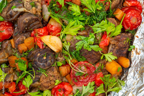 Close-up of delicious juicy meat baked in the oven with vegetables and decorated with fresh herbs. Food background