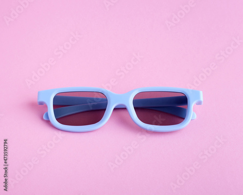 Blue 3D glasses on a pink background. View from above