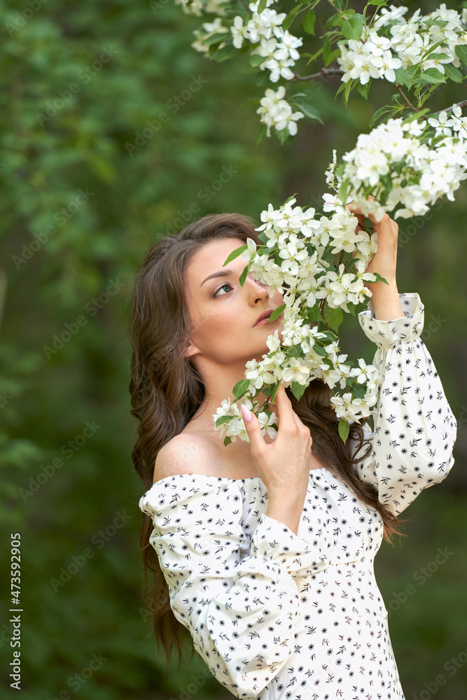Spring mood. A gentle image of a dreamy girl with a branch of a blooming apple tree in her hands.