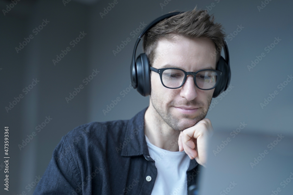 Smiling german man in headphones looking on screen of laptop and watching educational webinar Smiling german man in headphones looking on screen of laptop and watching educational webinar