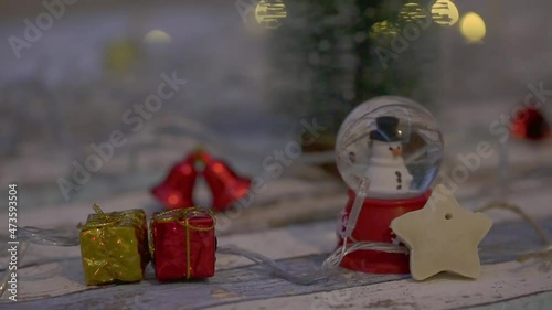 Zooming in snowman in globe with Christmas decors with christmas lights background
