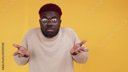 No idea. Clueless man. Doubt emotion. Boomerang motion. Uncertain African guy shrugging shoulders in dont know reaction isolated on free space orange background GIF loop. photo