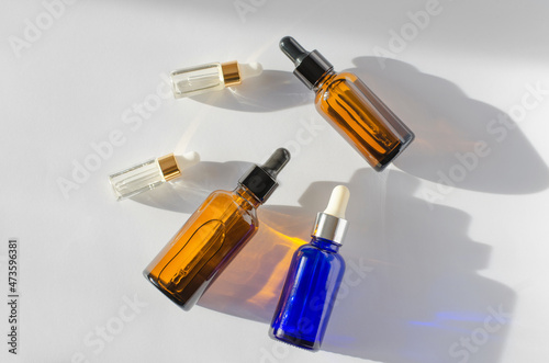 Bottles with essential oils of different colors and sizes on a white background with shadows