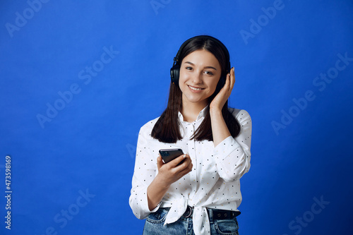 Young pretty girl looking at camera and listening to music with headphones.