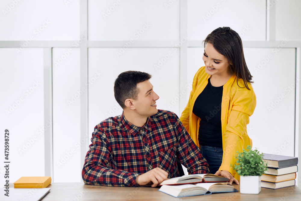 Two young students reading a book and preparing for an exam together. Two young students reading a book and preparing for an exam together.