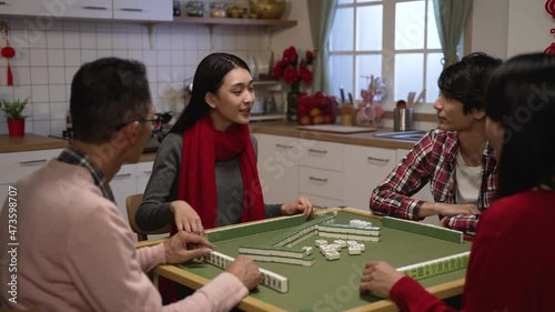 family members clapping hands for the winning daughter who claims a discarded tile and completes her hand while playing mahjong game at home on chinese new year's eve