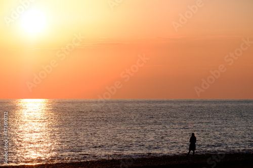 minimalism silhouette of a man on the seashore at sunset. orange sky and seashore
