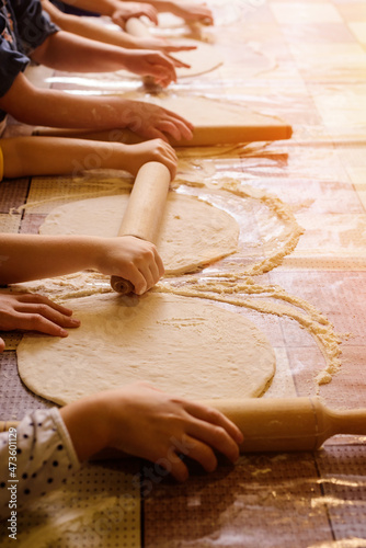 The hands of children knead the dough from which they will make bread, pasta, cake or pizza. 