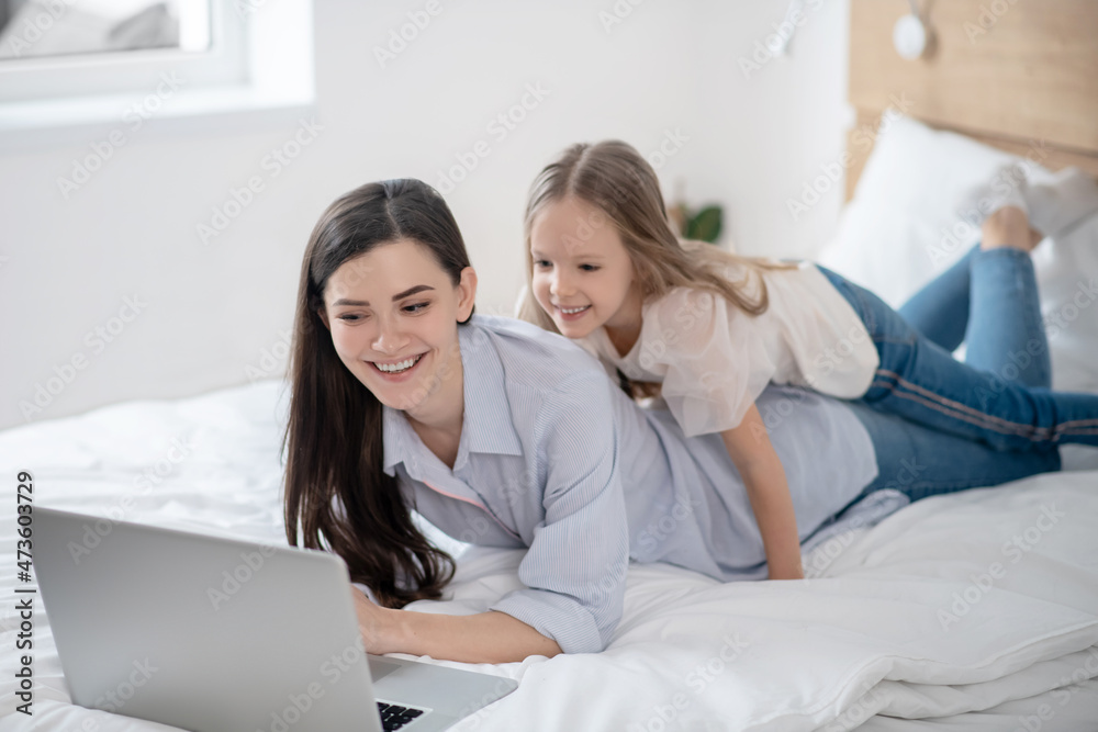 Kid and her mom watching a video on the laptop Kid and her mom watching a video on the laptop