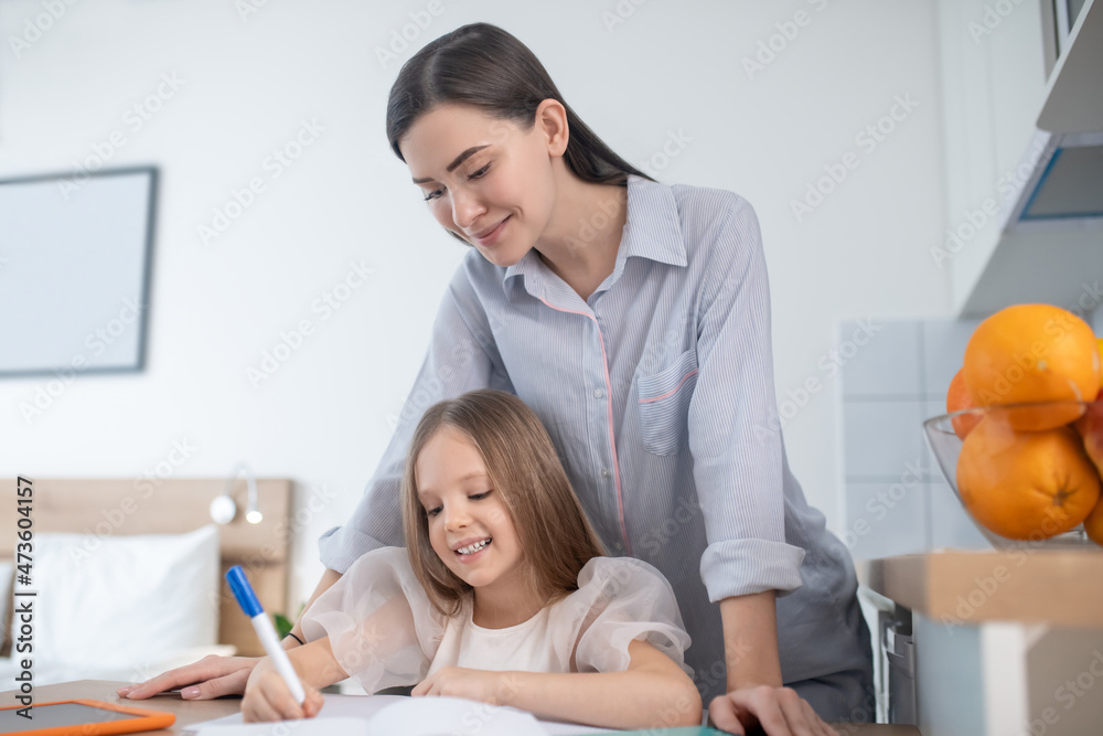 Young woman helping a little girl with homework Young woman helping a little girl with homework