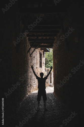 Vertical view of man outline with arms up in the air. Front view of person silhouette standing on a dark alley. Shapes and mockup concept of people doing poses.