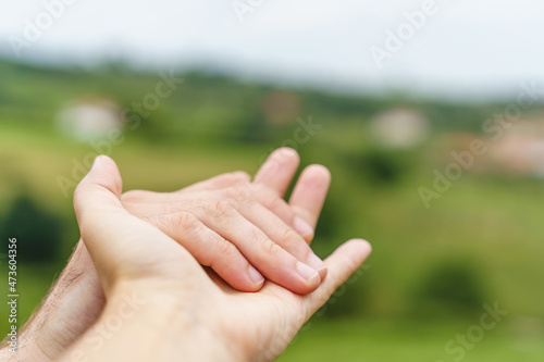 Close up view of unrecognizable couple holding hands on green background. Cropped horizontal view of unrecognizable caucasian people caressing hands. People an emotions concept. © beavera